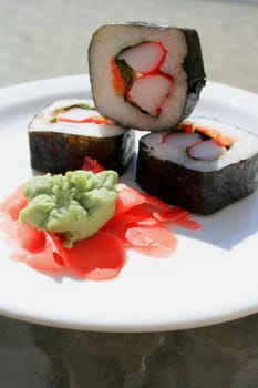 Sushi next to wasabi and sushi ginger on a platter.
