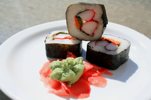 Sushi next to wasabi and sushi ginger on a platter.
