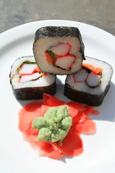 Sushi next to wasabi and sushi ginger on a platter.
