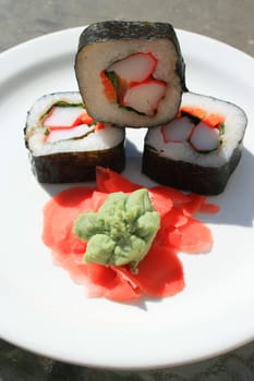 Sushi next to wasabi and sushi ginger on a platter.
