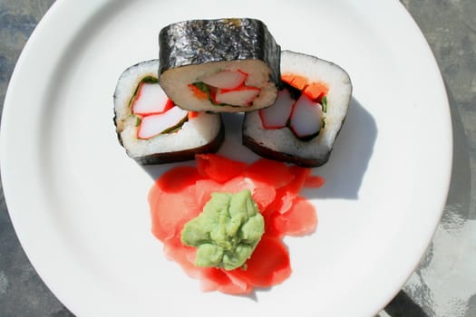 Sushi next to wasabi and sushi ginger on a platter.
