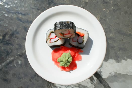 Sushi next to wasabi and sushi ginger on a platter.
