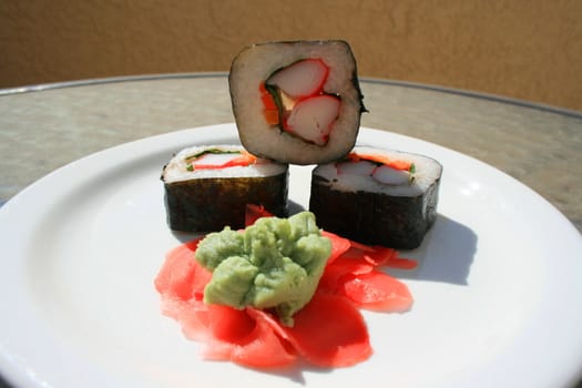 Sushi next to wasabi and sushi ginger on a platter.
