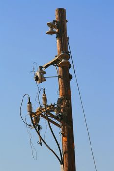 Close up of a telephone pole over blue sky.
