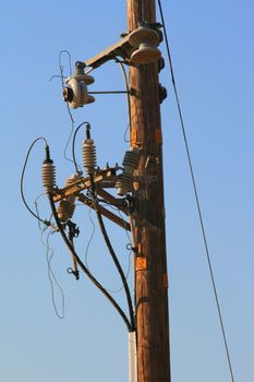 Close up of a telephone pole over blue sky.
