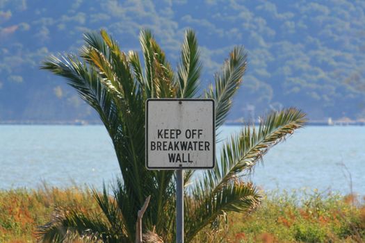 Keep off breakwater wall sign on a sunny day.
