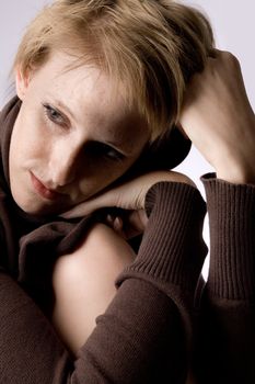 Studio portrait of a cute and beautifull girl in a turtle neck sweater in thoughts