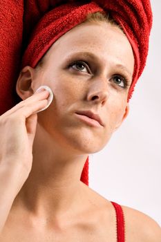 Studio portrait of a beautifull girl who is using a cotton pad on her face