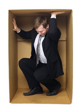 Well dressed businessman in a tight cardboard box isolated on white background