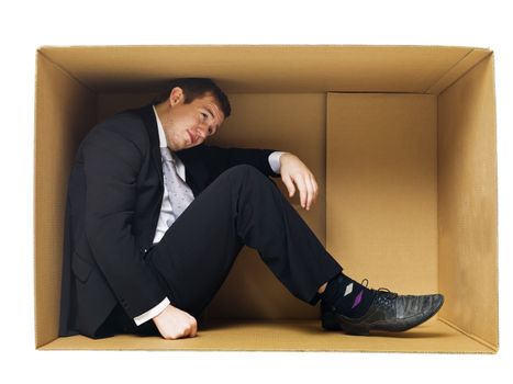 Businessman in a tight cardboard box isolated on white background