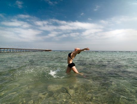 Young woman enjoying the sun standing in water