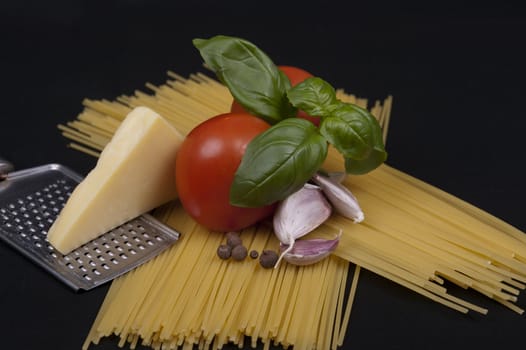  Spaghetti pasta, tomato, basil, garlic, black pepper and cheese isolated on a black background