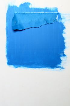 Plastic with blue painting and sheet of damaged paper over the blue steel wall