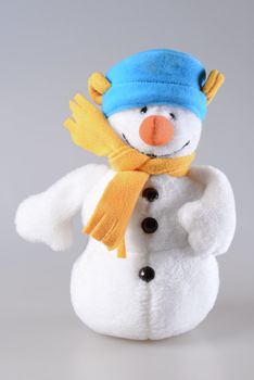 White toy plush snowman on grey background