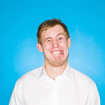 Young man making a funny face on blue background