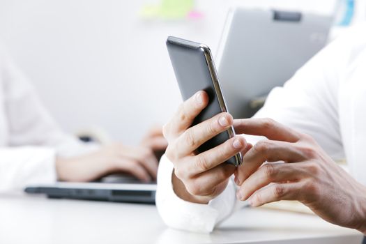 businessman using smart phone in office, hand close up