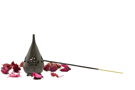 Incense stick in burner with red flower leaves 