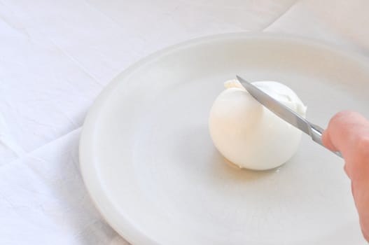 Cook hand cutting traditional Italian mozzarella di bufala (buffalo mozzarella) cheese made from buffalo milk