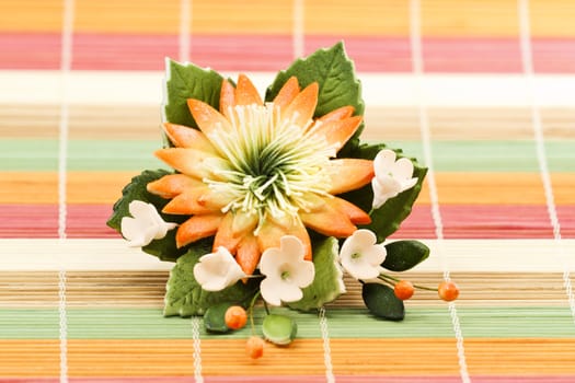 Multicolored flower decoration isolated on bamboo rug as a background