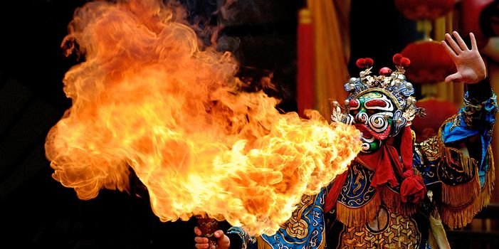 chinese opera actor make a show of spouting fire on stage.