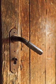 A century old rusty door knob on old wooden door