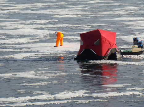 man ice fishing on a frozen lake