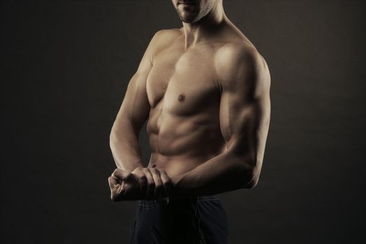 A shirtless male of a healthy fit young guy flexing his biceps