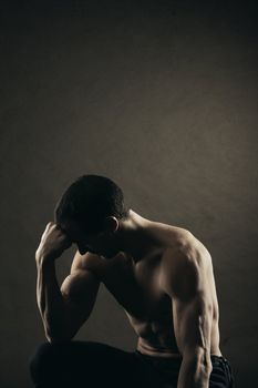 Bodybuilder concentrating on dark background