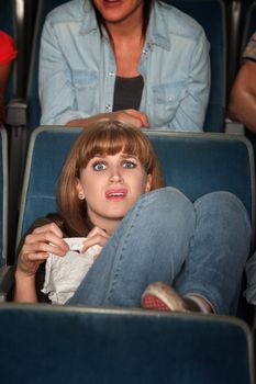 Young Caucasian woman holding tissue weeps in theater