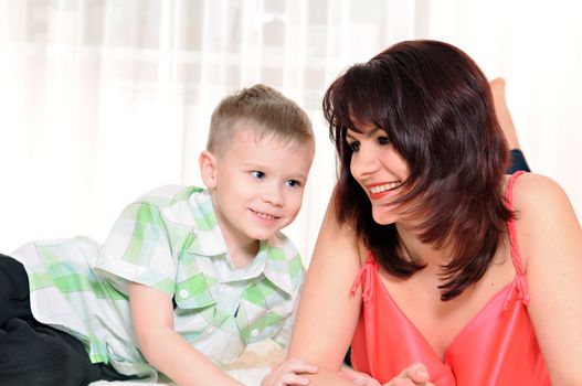 happy mother and son lie on the carpet