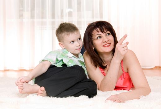 happy mother and son lie on the carpet