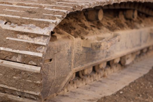 track of an excavator sitting on grass with dirt in the tracks