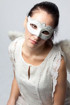 Young and beautiful girl in the mask and costume of an angel