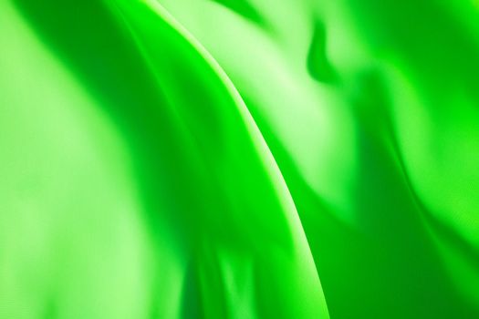 green fabric winds waves, creating a beautiful background of the folds