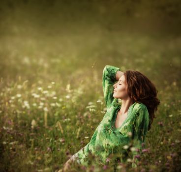Young beautiful woman enjoying nature in the flowers field