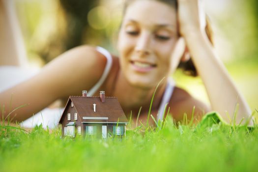 Young woman on a lawn looks at a small house