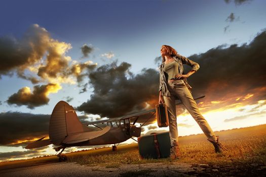 Fashion young womanl with a suitcase. Airplane in the background.