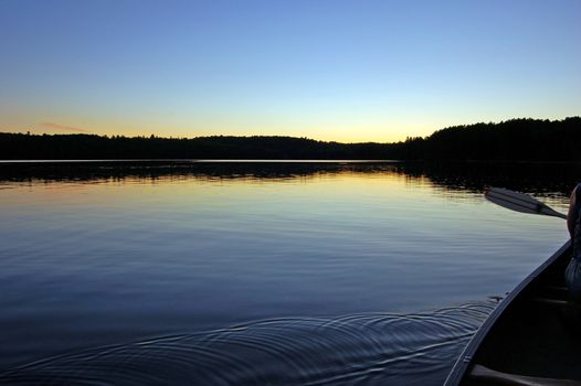 Sunset and canoe trip in calm lake in Algonquin Park
