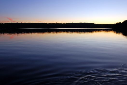 Sunset and canoe trip in calm lake in Algonquin Park