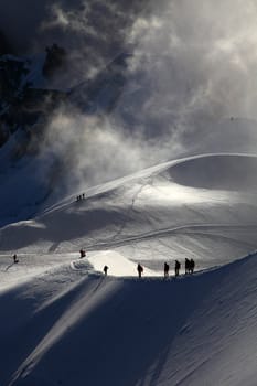 A group of alpinists on their way to the mont blanc at dawn.