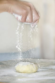 woman makes and prepares pastry in a bakery kitchen. Adding flour bits.