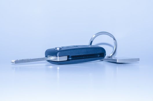 Blue toned isolated car key with keychain shadow and reflection