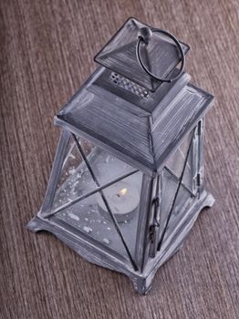 Close up of a gray iron lantern over wooden background