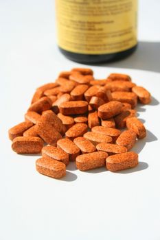 Pills next to a container on a white background.
