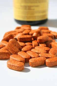 Pills next to a container on a white background.
