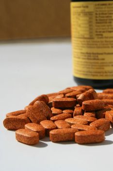 Pills next to a container on a white background.
