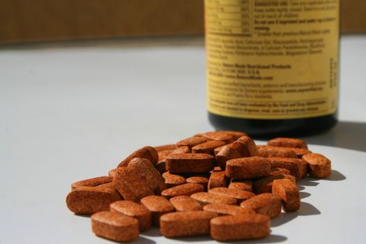 Pills next to a container on a white background.
