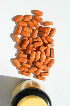 Pills next to a container on a white background.
