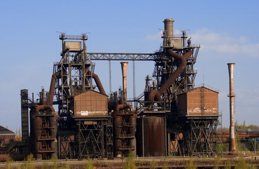 An obsolete industrial plant, with several chimneys and a lot of rust.