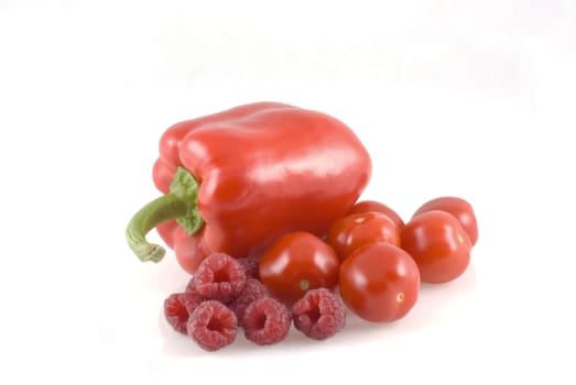 Red paprika, raspberries and cherry tomatoes on a white background.
